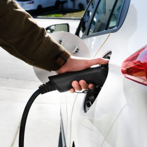 Hand is charging an electric car vehicle or EV at home charger.